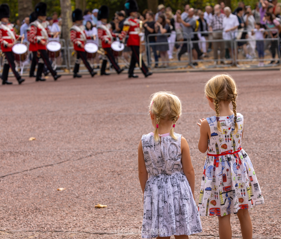 two young girls watching the march down The Mall