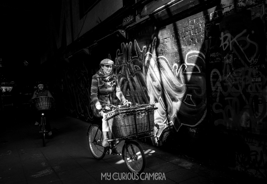 Lady riding through the Leake Street Tunnel on a bicycle with a basket on front