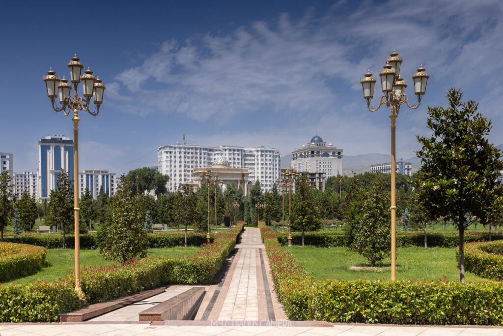 Alisher Navoi Park, recognizable by the beautiful central paved walkway, distinct golden streetlamps, and the white residential and government buildings framing the background skyline.